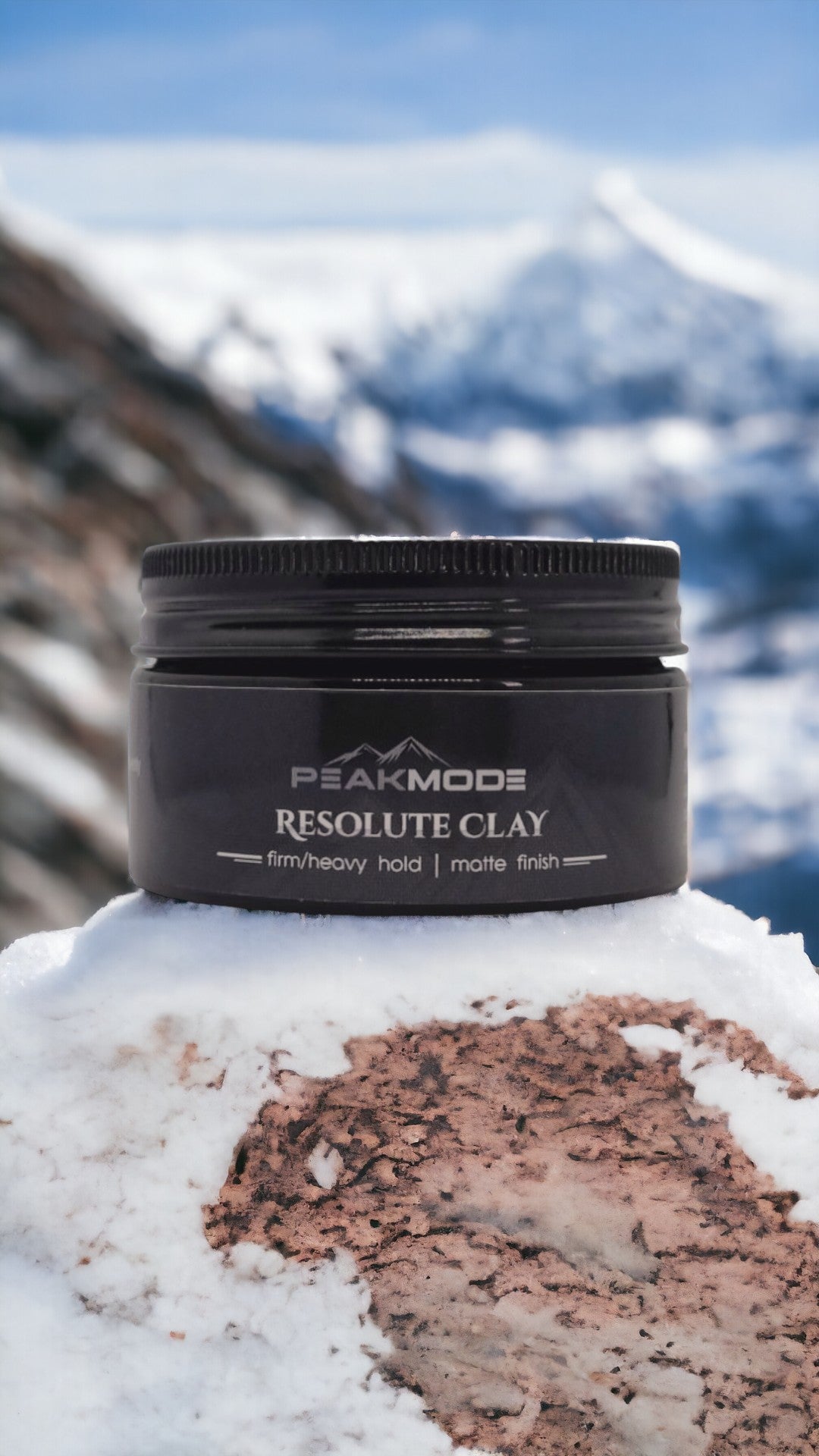 PEAKMODE resolute clay for men in a black container with firm hold and matte finish on snowy mountain background
